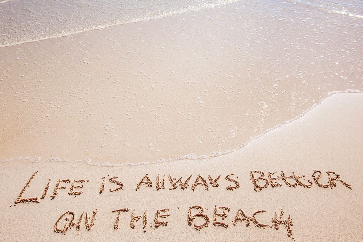 Life is always better on the beach written in the sand.