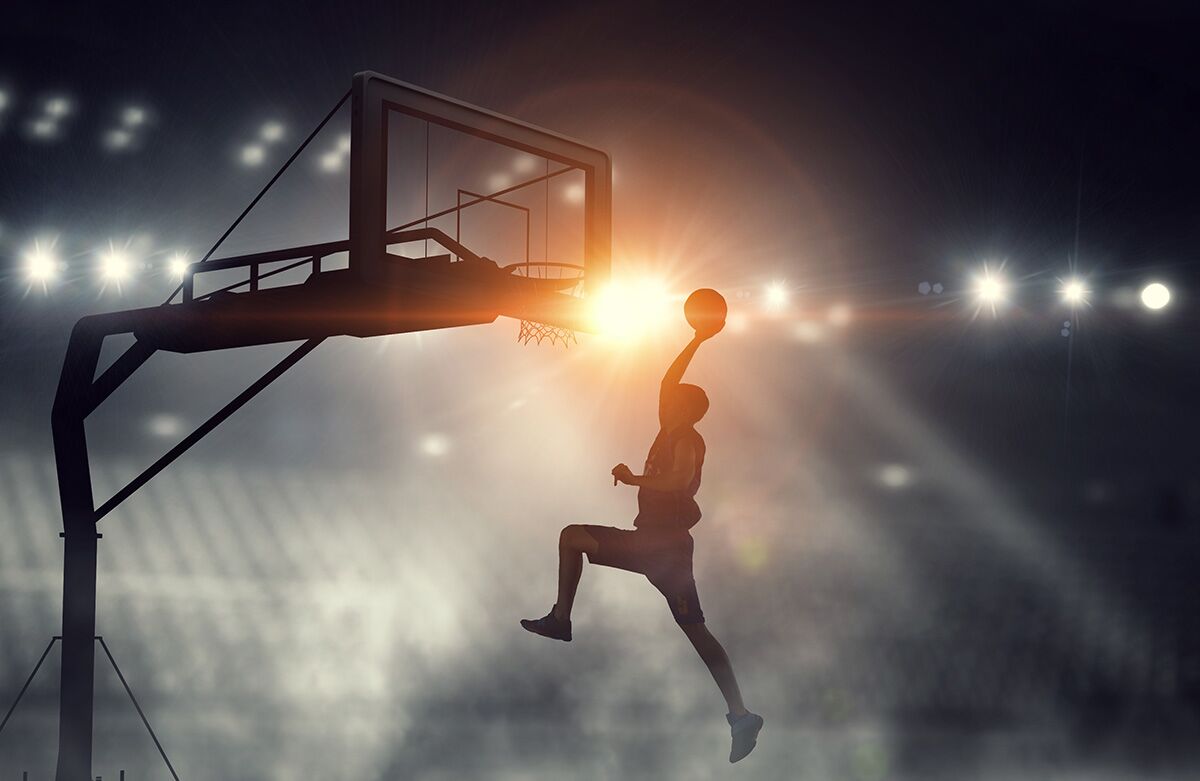 Basketball player dripping the ball in the net under floodlight.